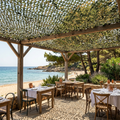 filet de camouflage vert jungle de Ombrela, devant la mer et au dessus de tables de restaurant